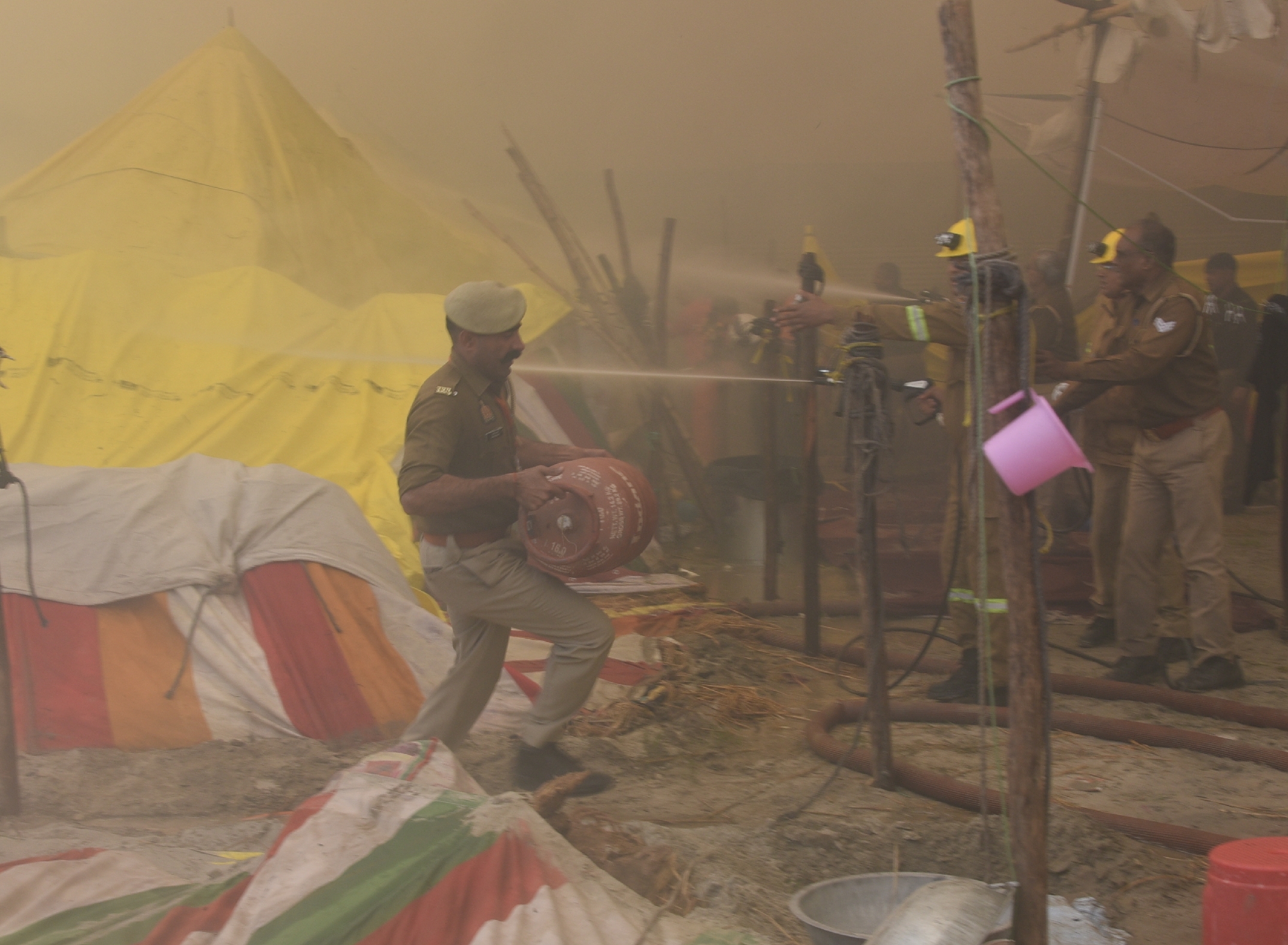 Close-up of a firetruck and firefighters working to control the blaze at Maha Kumbh 2025 amidst dense crowds