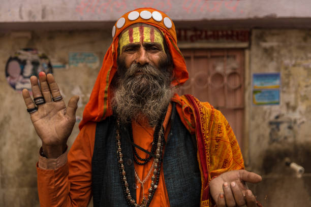 Allahabad, India - February 10, 2019: A Naga Sadhu (Indian holy man) blowing into a conch shell while bathing in the sacred Ganges river at Kumbh Mela Festival in Allahabad (Prayagraj), Uttar Pradesh, India.