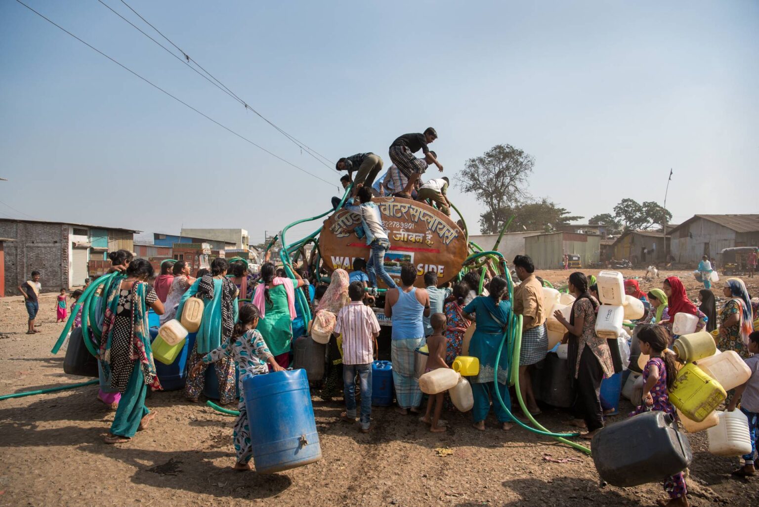 MAHARASHTRA/INDIA – MAY 15, 2016 : Residents climb a municipal water tanker to filling water in their containers in Bhiwandi
