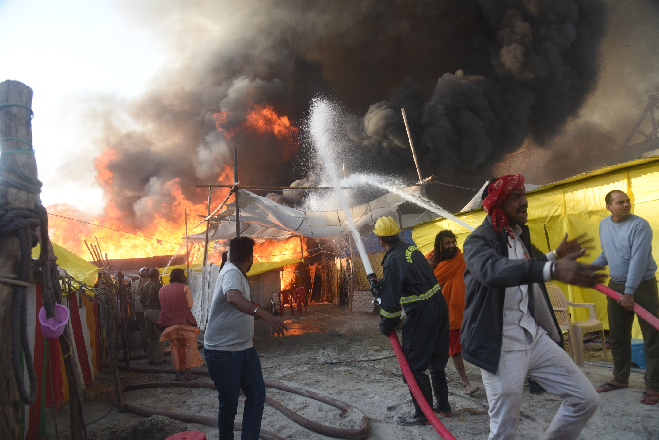 Crowds gathered at the Maha Kumbh site as flames from the fire consume tents in Sector 19, under the Shastri Bridge