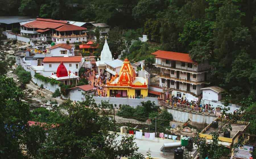 The serene Kainchi Dham temple surrounded by lush green hills, with the Kosi River flowing nearby. In the foreground, a portrait of Baba Neem Karori (Maharajji), radiating divine grace and presence, capturing the spiritual essence of the ashram